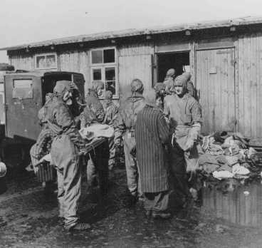 Soon after liberation, British medical officers begin disinfection of camp survivors. [LCID: 75116]