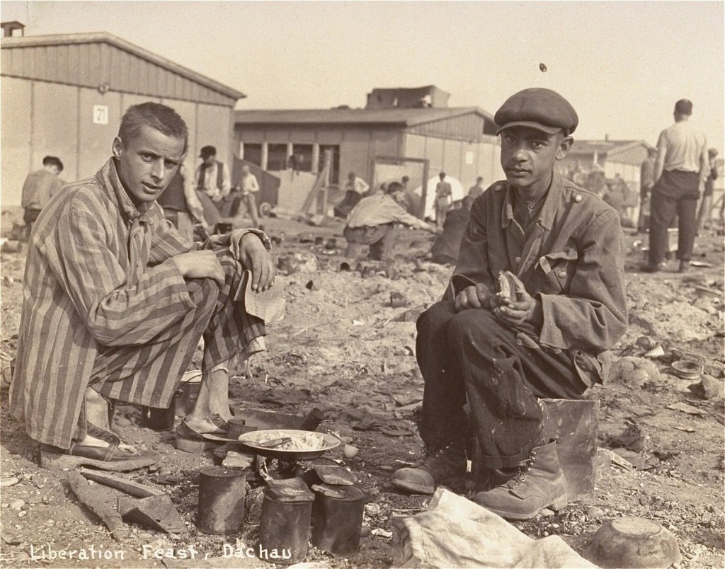Two survivors prepare food outside the barracks. [LCID: 74095]