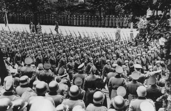 Adolf Hitler (lower right) gives Nazi salute as he reviews victorious German troops.