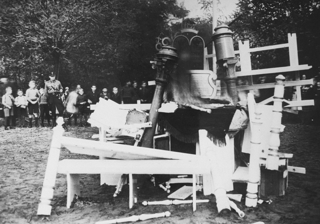 German children, behind an SS man, watch as religious objects from the Zeven synagogue are set on fire during Kristallnacht (the ... [LCID: 4318]