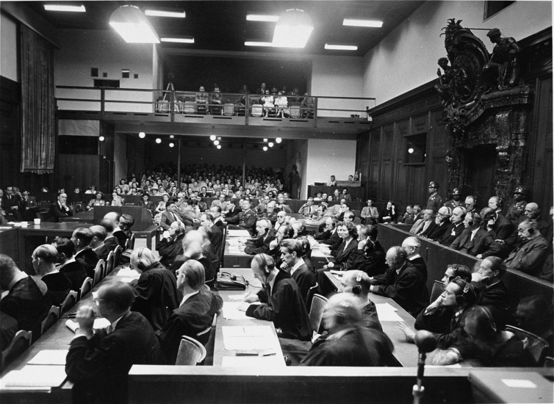 View of the courtroom as seen from the interpreters' section during the IG Farben Trial. The defense lawyers are in the foreground, the defendants are in the dock to the right, and the spectators' gallery is on the far side of the courtroom.
