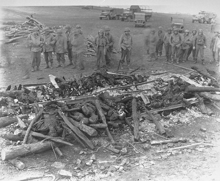 While on an inspection tour of the newly liberated Ohrdruf concentration camp, American soldiers view the charred remains of prisoners burned upon a section of railroad track during the evacuation of the camp.