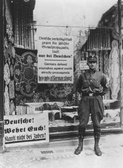 During the anti-Jewish boycott, an SA man stands outside a Jewish-owned store with a sign demanding that Germans not buy from Jews. [LCID: 4053]