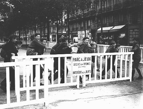 In German-occupied Paris, the fence around a children's public playground bears a sign forbidding entrance to Jews. [LCID: 01392]