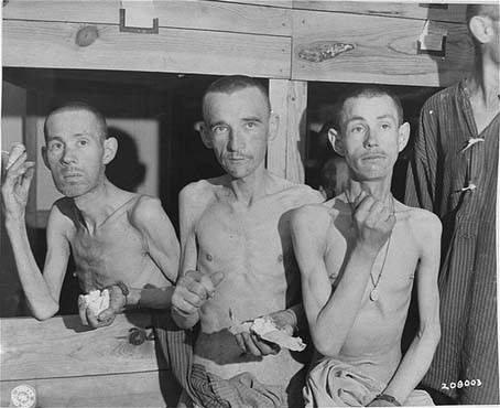 Emaciated survivors in the Ebensee subcamp of the Mauthausen concentration camp suck on sugar cubes provided by American soldiers upon the liberation of the camp.