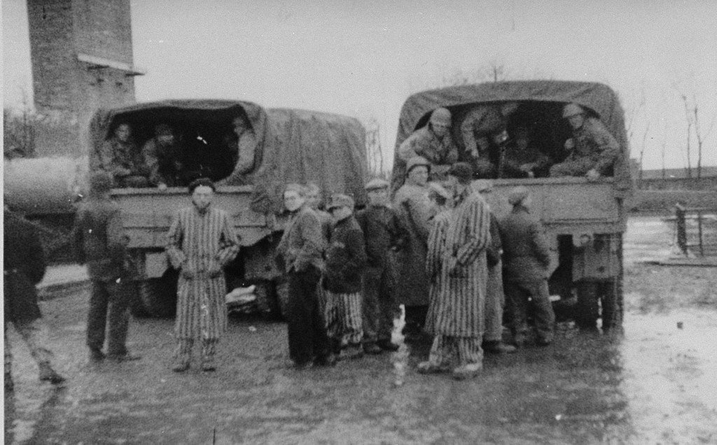 Survivors of the Buchenwald concentration camp gather around trucks carrying American troops. [LCID: 04064]