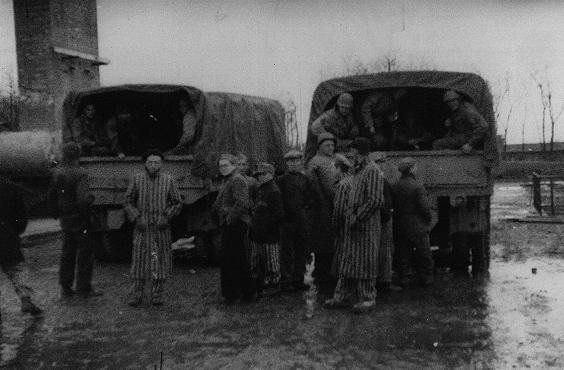 Survivors of the Buchenwald concentration camp gather around trucks carrying American troops.