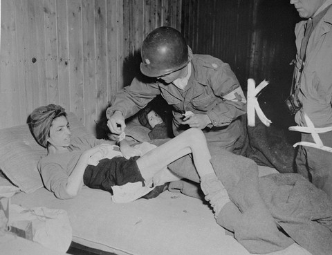 Lt. Col. J.W. Branch, Chief Surgeon of the 6th Armored Division, provides medical care to a Hungarian survivor in Penig, a subcamp ... [LCID: 04444]