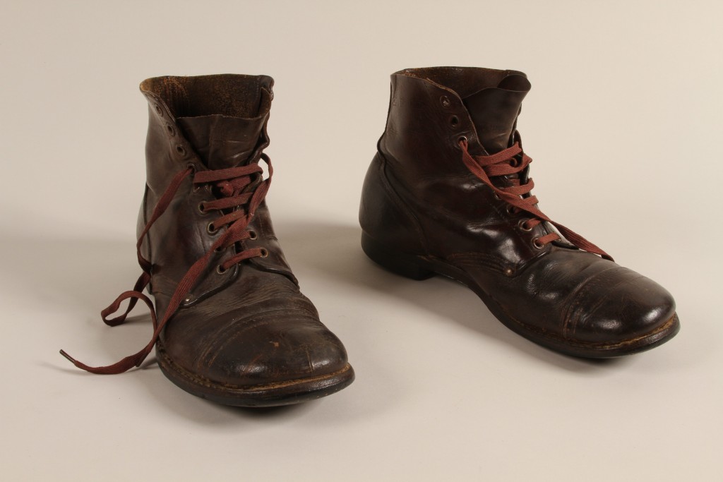 Pair of worn dark brown leather boots with reddish brown laces.