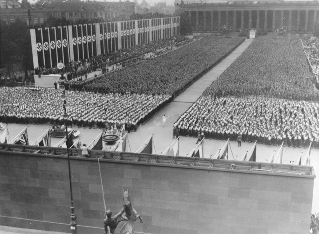 <p>Le 1er août 1936, Hitler ouvrit les XIe Jeux olympiques d'été à Berlin, en Allemagne. Inaugurant un nouveau rituel olympique, un coureur portait une torche transmise en relais depuis le site des anciens jeux à Olympie, en Grèce. Cette photographie représente le dernier coureur à son arrivée à Berlin, la torche olympique à la main. Il va allumer la flamme olympique, marquant ainsi le début des XIe Jeux olympiques d'été. Berlin, Allemagne, 1er août 1936.</p>