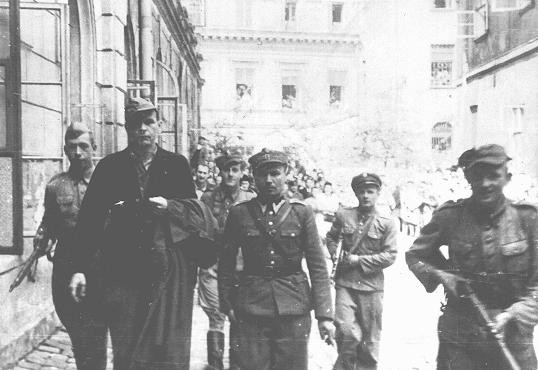 Amon Goeth (front left), commandant of the Plaszow camp, under escort to the courthouse in Krakow for sentencing. [LCID: 03410]