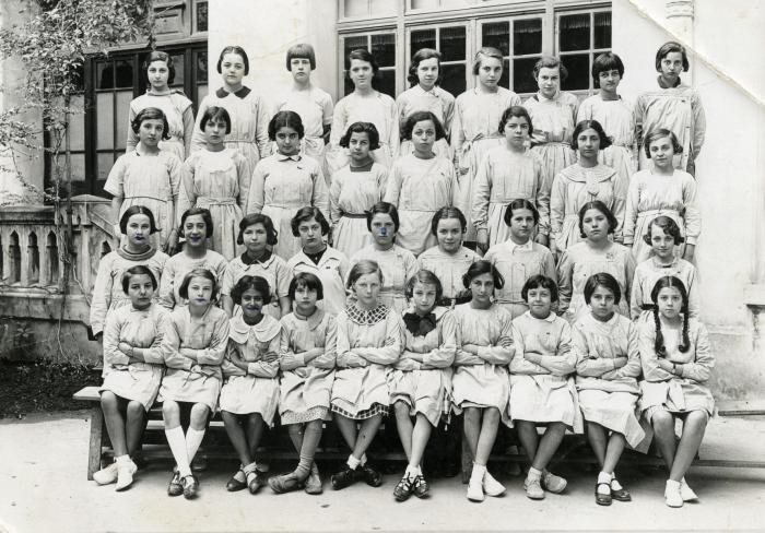 A group of Tunisian schoolgirls wearing aprons. Nadia Cohen is in the first row - 3rd from the left.