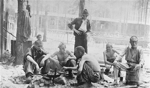  Survivors of the Ebensee concentration camp cook a meal over an open fire after the liberation of the camp. [LCID: 66895]