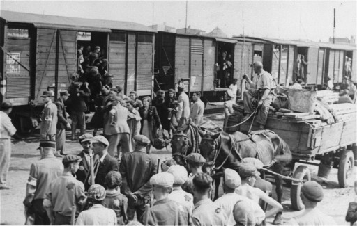 Groups of people wait next to a mule-drawn wooden cart to board a long line of rail cars. Smaller groups are in the process of getting into the rail cars.