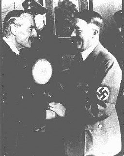 British prime minister Neville Chamberlain and German chancellor Adolf Hitler greet each other at the Munich conference. [LCID: 74614]