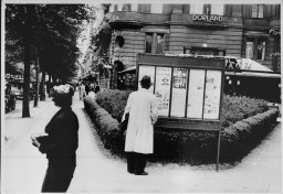 A pedestrian stops to read an issue of the antisemitic newspaper "Der Stuermer" (The Attacker) in a Berlin display box. [LCID: 02629]