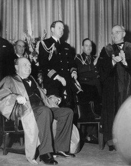 Winston Churchill (seated) at Westminster College on March 5, 1946, the day he delivered his “Iron Curtain” speech. Standing at the far right is US President Harry S. Truman. Photograph taken by Terry Savage. Fulton, Missouri.