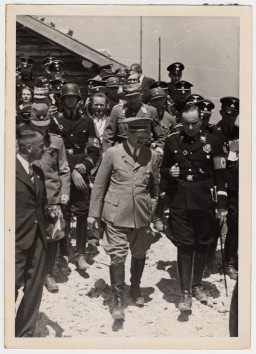 Adolf Hitler walks and converses in a group with other Nazis