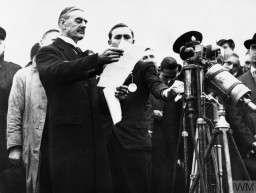 Neville Chamberlain addresses a crowd at the Heston Aerodrome after signing the Munich Agreement on September 30, 1938. He will later deliver a speech at 10 Downing Street, where he proclaims, “I believe it is peace for our time.” IWM (HU 4255)