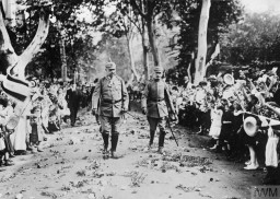Field Marshal Paul von Hindenburg walks along a flower-covered path on his 70th birthday. On either side, crowds of children cheer. October 2, 1917. Hindenburg will later be elected president of Germany in 1925. © IWM Q 23976