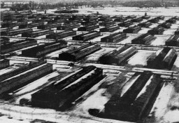A grainy black and white aerial photo of several rows of long barracks in the snow.