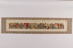 A framed woodblock print in multiple colors. Print is of a long city street with various businesses and homes.