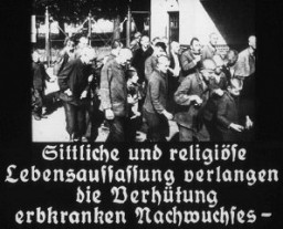 Bu görüntü Reich Propaganda Bakanlığı tarafından çekilen bir filmden alınmıştır. Başlığı şöyledir: “Hayatın ahlakî ve dinî kavrayışı kalıtsal olarak hasta evlatların doğmamasını gerektirir”. Nazi propagandası zorunlu kısırlaştırma çabaları için kamu desteği oluşturmayı hedefliyordu.