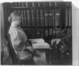 Portrait of Helen Keller, seated, reading Braille