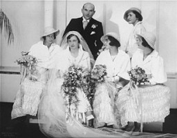 Portrait of Hilde and Gerrit Verdoner, with four bridesmaids, on their wedding day. The bridesmaids are: Jetty Fontijn (far left), Letty Stibbe (second from right), Miepje Slulizer (right), and Fanny Schoenfeld (standing, back). Amsterdam, the Netherlands, December 12, 1933.