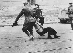  German soldier watches Ukrainian civilians drag a Jew down a street in Lvov. [LCID: 69737]