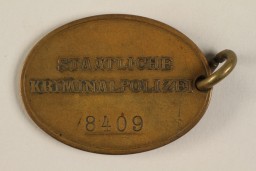 Reverse of a Kripo warrant disc listing the officer's number