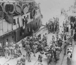 Le fonctionnaire de l'ONU Emil Sandstroem (en bas à droite avec le chapeau blanc) regarde des soldats britanniques évacuer les réfugiés juifs de "lExodus 1947." Les passagers furent renvoyés en Europe. Haïfa, Palestine, le 20 juillet 1947.