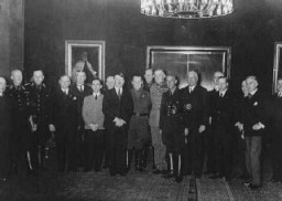 آدولف هیتلر کمی پس از رسیدن به مصدر قدرت به عنوان صدر اعظم آلمان همراه با کابینه خود درحال آماده شدن برای عکسبرداری. در سمت چپ هیتلر جوزف گوبلز و در سمت راست وی هرمان گورینگ قرار دارند. برلين، آلمان، ۱۹۳۳