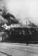 A building burns during the suppression of the Warsaw ghetto uprising. The photograph was taken through the window of a building adjacent to the ghetto. Warsaw, Poland, May 1943.