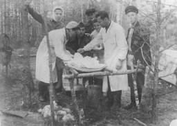 A wounded partisan is treated in a field hospital belonging to the Shish detachment of the Molotov brigade. Among those pictured are Dr. Ivan Khudyakov, the brigade's physician (second from the right), and Fanya Lazebnik (Faye Schulman), a photographer and partisan nurse (left). The wounded partisan's name is Sergei. Pinsk, 1942–44.