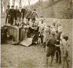 A group of young boys pose on and next to the demolished vehicle of local Jewish teacher Ferdinand Stern. The car had been driven to a nearby lake and set on fire during Kristallnacht. Frankenberg, Germany, November 1938.