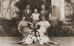 Members of the Amarillo family pose outside their home in Salonika. Front, from left to right, are Tillie Amarillo and Sarika Yahiel. Seated behind them are their mothers Louisa Bourla Amarillo and Regina Amarillo Yahiel. Standing are Saul Amarillo, Isaccino Yahiel, and Isaac Yahiel. Salonika, Greece, between 1930 and 1939.