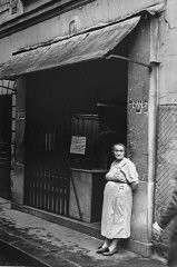 In the Jewish quarter of Paris, a Jewish woman wearing the compulsory Jewish badge stands at the entrance to a kosher butcher shop. France, between May 1942 and 1944.