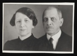 Black and white photograph taken in a studio of a woman in a dark dress with her hair up and a man in a suit.
