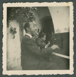 From the start, jazz music was often associated with race all over the world. Begging the question, could the spirit of jazz stand against racial oppression?
Jazz was described as “musical dictatorship over the masses,” “utterly impoverished,” and “culturally repulsive.” In the early 1920s, African American jazz artists could not break through the racial divide in the US, so they took to Europe where they could perform with ever-growing popularity. The cultural movement of this music threatened the expansion of Nazi ideology, which deemed this music to be immoral. By the mid-1930s Nazi authorities banned all foreign, non-Aryan music in Germany.
The campaign to rid the country of jazz did not stop American artists from going abroad to share their art. For African American horn and piano player Freddy Johnson, who was on tour, the threat became real. In December 1941, he was arrested in German-occupied Amsterdam and interned at the Tittmoning prisoner-of-war camp.
Once in awhile, despite the oppression of prisoners in the camps across German-occupied Europe, the sounds of jazz could be heard. For many, musical talents helped them survive another day.
In February 1944, Johnson was released from the camp in a prisoner exchange. 