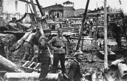 SS men supervise laborers at construction work. Neuengamme concentration camp, Germany, winter 1943. [LCID: 55244]