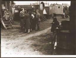 Dr. Robert Ritter talks to several residents in a Zigeunerlager ("Gypsy camp"). Hamburg, Germany, 1940.
During the Nazi era, Dr. Robert Ritter was a leading authority on the racial classification of people pejoratively labeled “Zigeuner” (“Gypsies”). Ritter’s research was in a field called eugenics, or what the Nazis called “racial hygiene.” Ritter worked with a small team of racial hygienists. Among them were Eva Justin and Sophie Ehrhardt. Most of the people whom Ritter studied and classified as Zigeuner were German Roma called Sinti. Sinti are a subgroup of Romani peoples. 
In 1935, municipal authorities across Nazi Germany began to force Romani families to move into Zigeunerlager (“Gypsy camps”). Eventually, these camps were centralized under the authority of the Nazi Kripo (criminal police). Ritter and his team regularly examined the individuals in these camps. They sometimes used threats or bribes to force people to cooperate. The creation of these camps was one of the Nazis’ early steps toward the genocide of Romani peoples. Many Romani victims were later deported to concentration camps, ghettos, or killing centers. 
Source Record ID: Bild 146/87/114/77