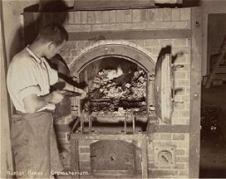 A survivor stokes smoldering human remains in a crematorium oven that was still lit in the Dachau camp. Photograph taken upon the liberation of the camp. Dachau, Germany, April 29-May 1, 1945.