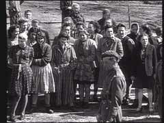 After British soldiers liberated the Bergen-Belsen concentration camp in Germany, they forced the remaining SS guards to help bury the dead. Here, survivors of the camp taunt their former tormentors, who prepare to bury victims in a mass grave.