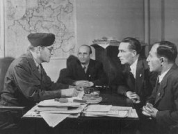 Membres de la communauté juive allemande rencontrant David Wodlinger (à gauche) du Joint (le Joint Distribution Committee, organisation caritative juive américaine - JDC). Camp de personnes déplacées de Bergen-Belsen. Allemagne, après la libération, avril 1945.