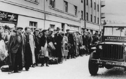 Réfugiés juifs ayant fui la Pologne dans le cadre de la Brihah (fuite massive des Juifs d’Europe orientale après-guerre) faisant la queue dans les rues à l’extérieur d’un centre d’accueil. Nachod, Tchécoslovaquie, juillet 1946.