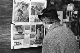 In Berlin, a German woman reads a copy of the Berliner Illustrierte newspaper, featuring photographs of Mussolini's official visit to Berlin in September 1937.