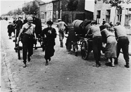 Juifs au travail forcé, transportant des excréments dans une rue du ghetto.
