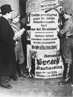 SA men post signs demanding that Germans boycott Jewish-owned businesses. [LCID: 4049]
