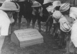 Polish Jewish refugee children known as the "Tehran Children" gather at a memorial stone dedicated to the Jewish refugees who died when the Patria (a ship bound for Palestine) sank in November 1940. Atlit, Palestine, 1943.